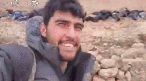 صورة إرهابي يسخر من ضحايا مجزرة ارتكبها في إحدى قرى عين العرب. أكثر من 21 مدنيًا، أغلبهم أطفال ونساء، أُعدموا بدم بارد على أيدي عناصر «قسد».